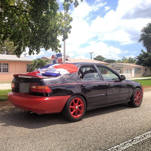 Car with red rims and prideful flags